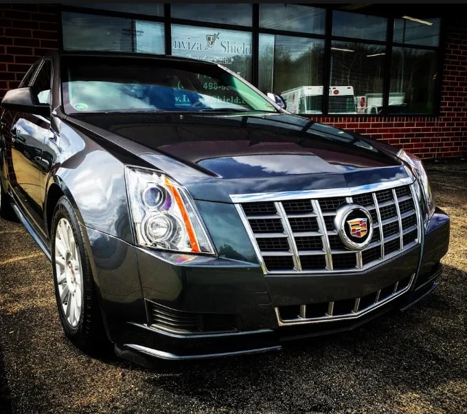 Black Cadillac luxury sedan parked in front of a brick building showroom