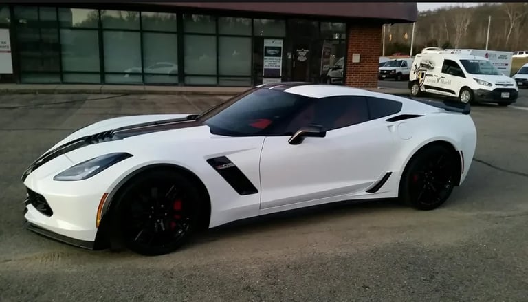 White Chevrolet Corvette sports car with black accents parked in a commercial lot