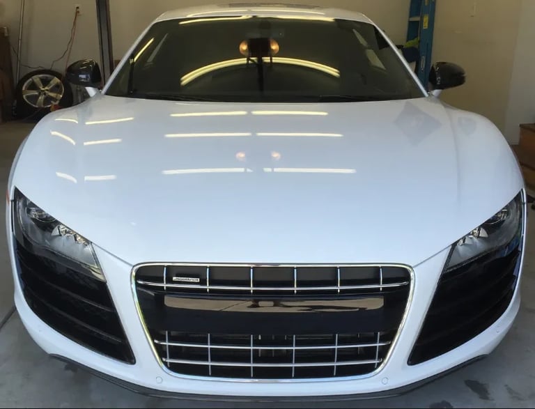 White sports car front view in garage with black grille and headlights